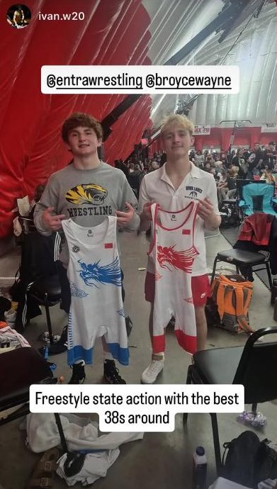 Two wrestlers at a tournament holding up their Entra singlets